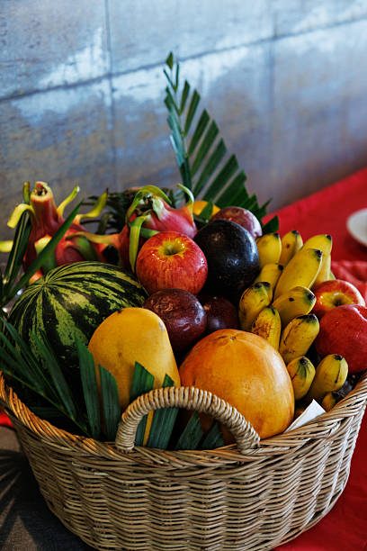 istock Assorted fresh fruits displayed in a wicker basket with tropical leaves for decoration 2214060747
