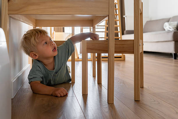 istock Curious Toddler Playing and Exploring Under Chair at Home 2214061668