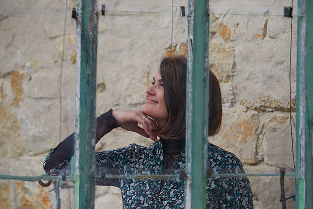 Woman in Melancholic Thought Posing by Rustic Window Frame Exterior View
