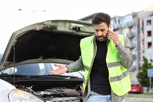 Rear view of unrecognizable man wearing mechanic holding his lower back in discomfort due to pain at repair shop
