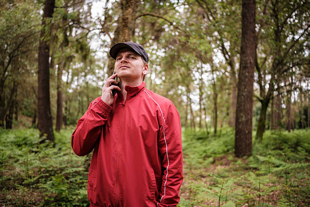 sportsman wearing red jacket talking on phone in forest