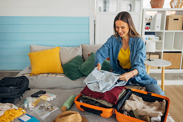 istock A smiling woman neatly arranges her wardrobe in a suitcase, while packing for a trip 2214073389