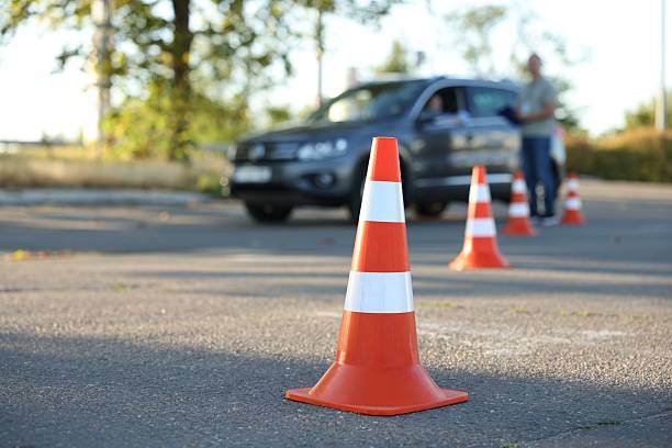 istock Examiner instructing student before exam at driving school test track, focus on traffic cone 2214073693