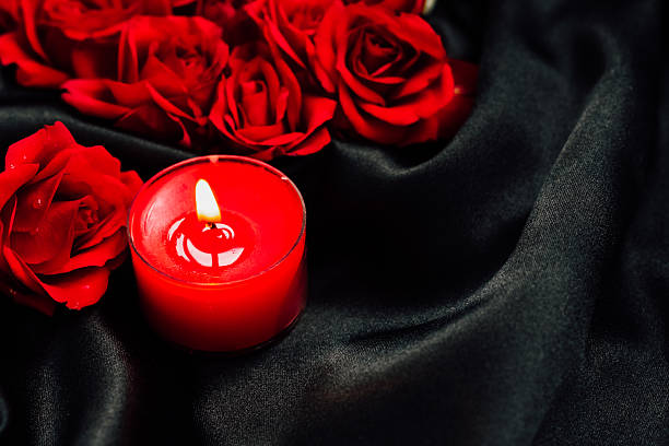 istock Red roses and candle create romantic atmosphere on black silk background 2214074973