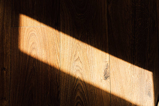 istock Light casts shadow on wooden floor creating a serene atmosphere indoors 2214075040