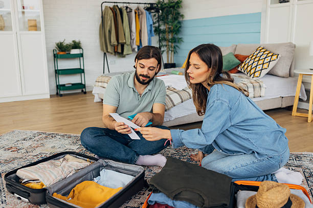 istock A loving couple prepares airplane tickets while packing for a weekend trip, checking what time their flight is 2214075401