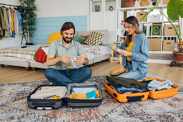 istock Man putting plastic cosmetic airplane kit into suitcase while packing for a trip with his girlfriend 2214076621