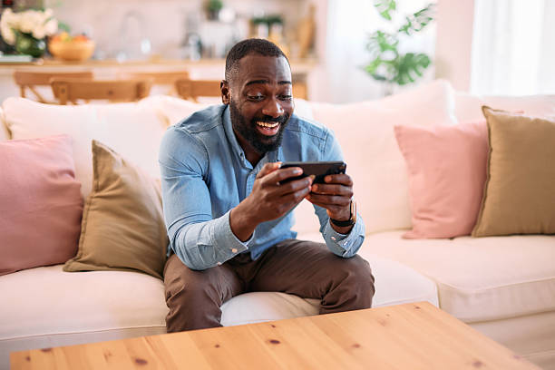 istock Young man playing mobile games on the sofa at home 2214076781