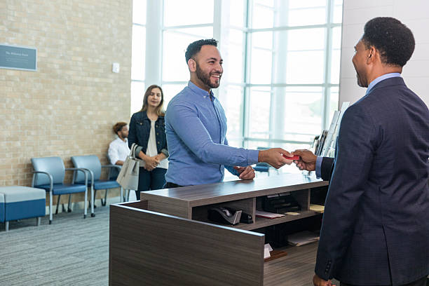 istock Man handing ID card at reception desk, people smiling 2214081832