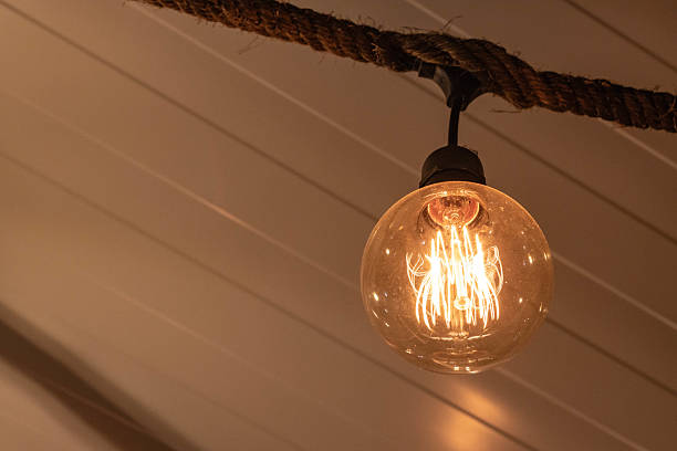 istock Warm glowing Edison-style vintage filament bulb hanging from rustic rope fixture 2214088933