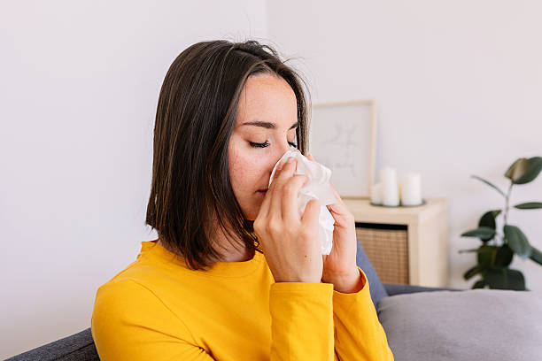 istock Sick young woman with common cold feeling pain blowing nose with tissue 2214089317