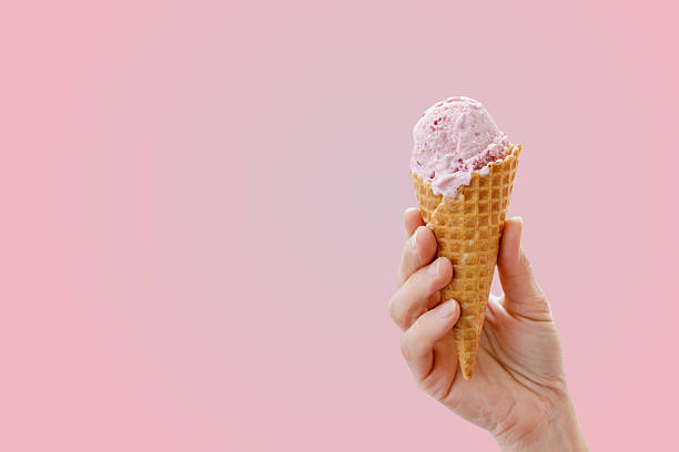 istock Hand holding a waffle cone with strawberry ice cream 2214093023