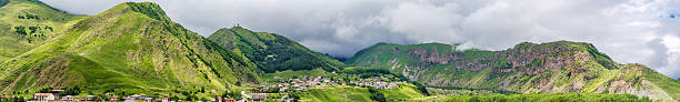 istock Panoramic view of Kazbegi mountains with Gergeti Trinity Church and Stepantsminda village under dramatic clouds. Travel in Georgia. 2214094782