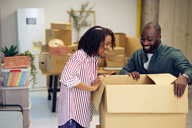 istock Young Couple Unpacking Cardboard Box In New Office 2214105145