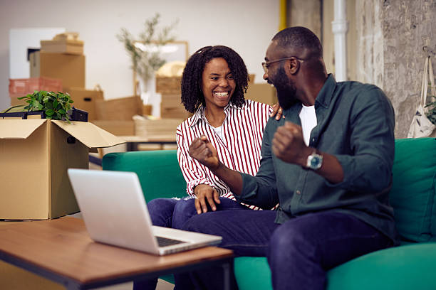 istock Happy couple celebrating moving into new home using laptop 2214105270