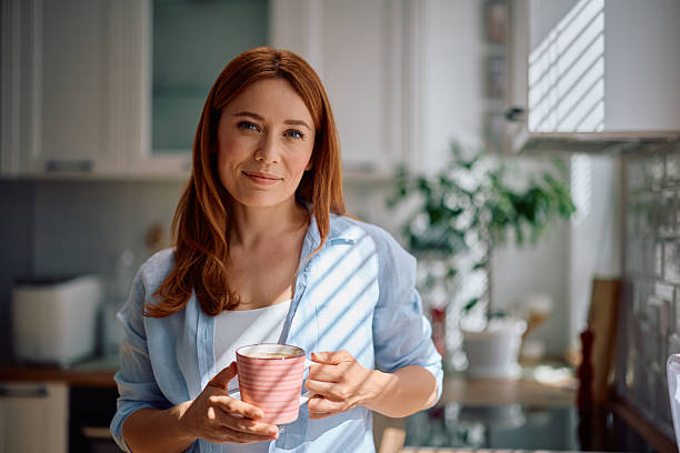 istock Smiling woman drinking coffee at home and looking at camera. 2214112009