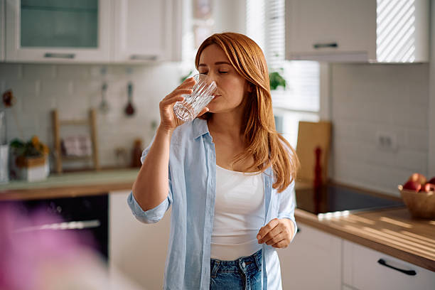 istock Woman with eyes closed drinking water at home. 2214112171