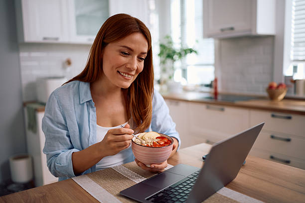 istock Happy woman using laptop while having oatmeal with fresh fruit at home. 2214112739