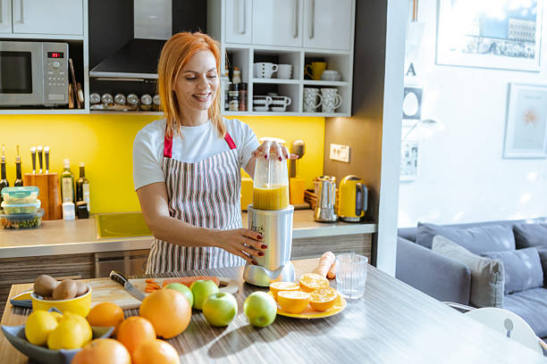 istock Woman making fresh fruit juice in a modern kitchen with natural light 2214120765