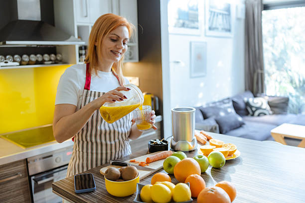 istock Woman preparing fresh orange juice in a cozy modern kitchen 2214120816