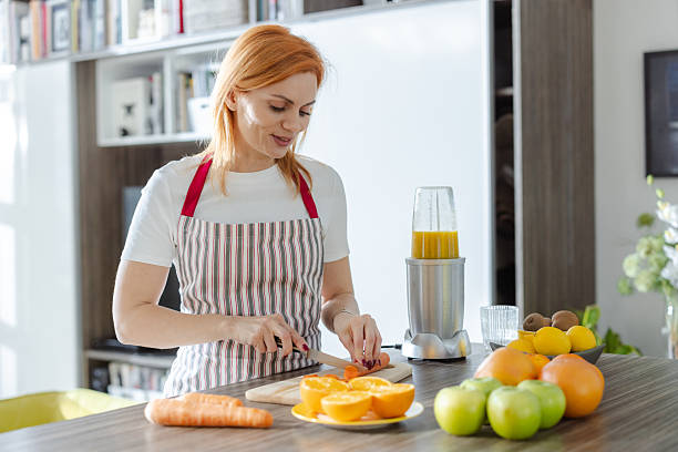 istock Woman preparing fresh fruit juice in a bright, modern living space 2214121677
