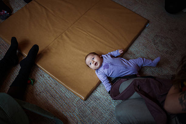 istock Cute baby lying on mat at mommy and baby support group 2214122282