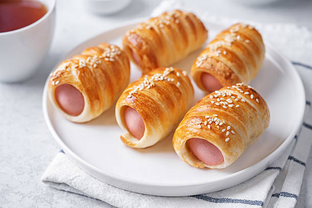 istock Sausage in dough, hot dog bread mini in a plate on a white background 2214122391