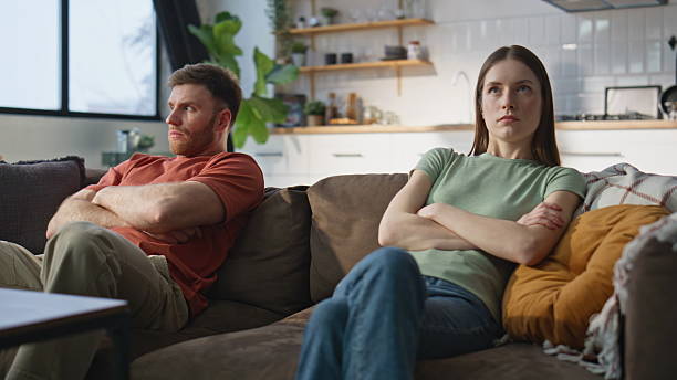 istock Married couple resent sitting separately home couch closeup. Frustrated partners 2214127848