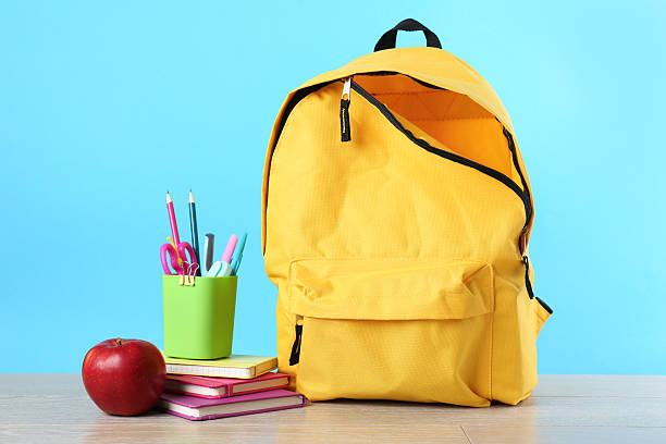 istock Backpack with different school stationery and apple on wooden table against light blue background 2214128791