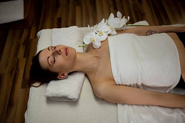 A tranquil and serene spa session featuring a woman fully immersed in relaxation surrounded by beautiful flowers