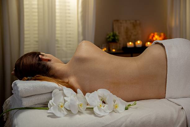 Spa stones, rolled towels and herbal bags on massage table indoors