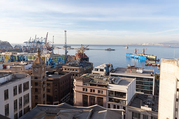 04/05/2025: Valparaíso, Chile. Panoramic view of the port of Valparaiso from one of its many tourist hills, with its cranes, pier, and boats. Next to the buildings of the city center in the evening light. In the background, you can see the city of Reñaca.