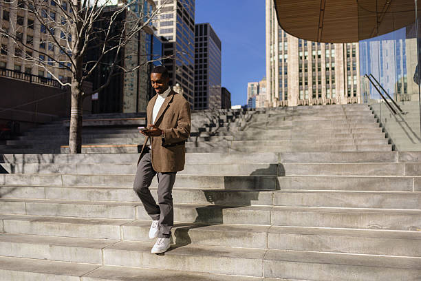 istock Businessman walking down stairs in city using smartphone 2214138192