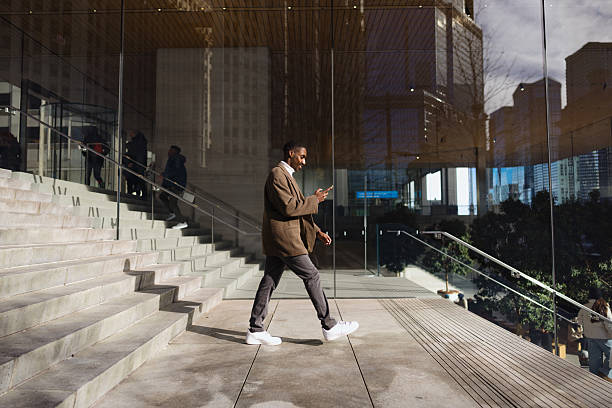 Businessman walking and using smartphone in urban modern environment