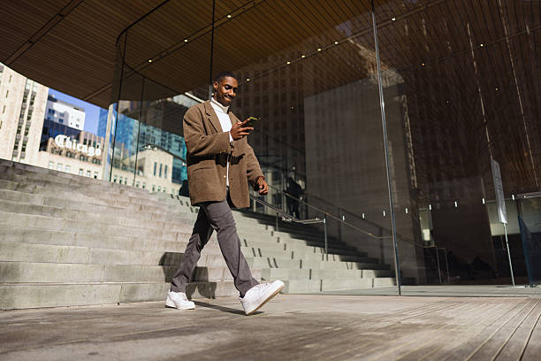 istock Young businessman using phone while walking in a modern city 2214138208