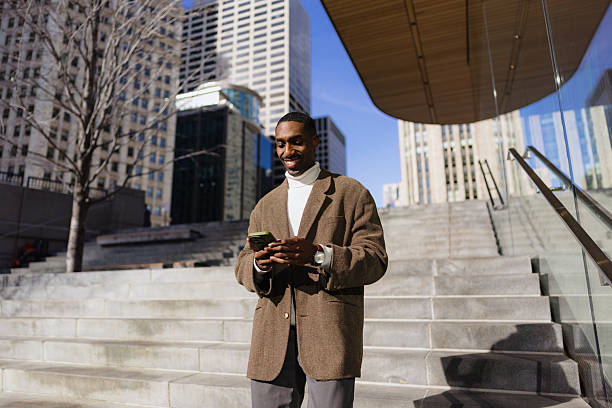 istock Smiling businessman using smartphone on city steps in front of modern building 2214138210