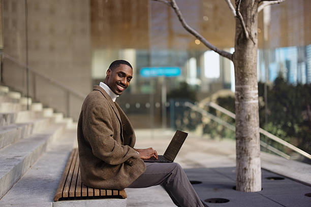 istock Smiling businessman working on laptop outdoors in urban setting 2214138222