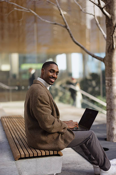 istock Smiling businessman working on laptop outdoors in urban setting 2214138225