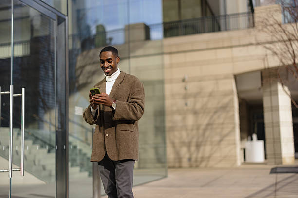 istock Smiling businessman using smartphone in front of office building 2214138246