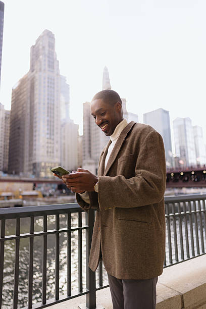 istock Young professional enjoying a moment by the chicago river, using his phone and smiling 2214138265