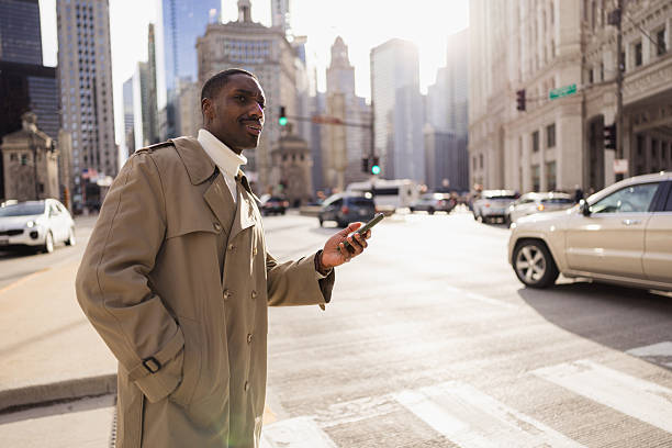 istock Businessman using smartphone app ordering taxi cab in chicago downtown 2214138328