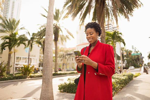 Smiling young woman using smartphone on a city sidewalk