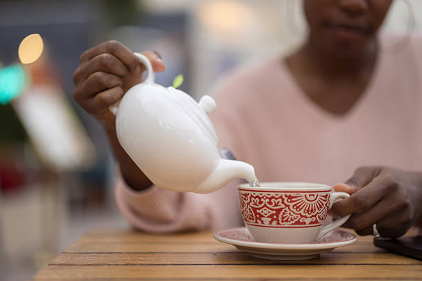 istock Young woman pouring tea into a cup at a cafe 2214138465