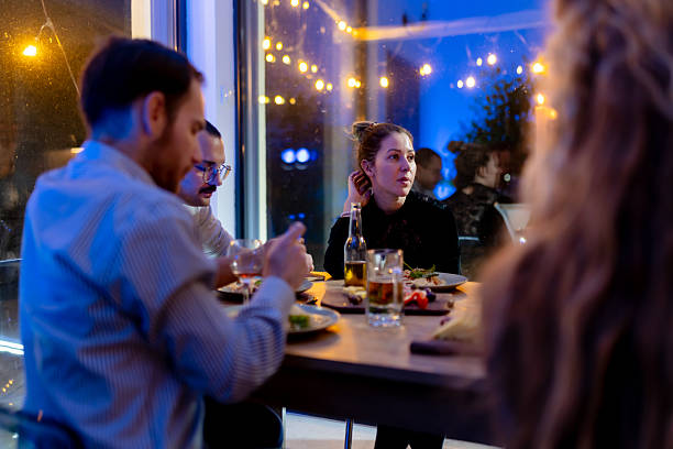istock Friends enjoying a dinner gathering in a warm, festive atmosphere with conversations and good food under cozy lighting at a restaurant. 2214145587