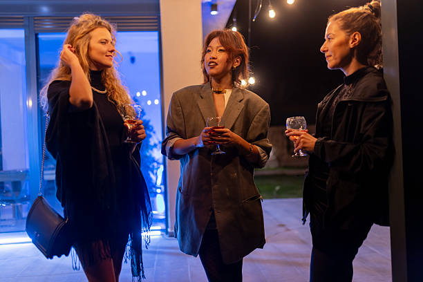 istock Three women enjoying a lively evening gathering with conversation and drinks under decorative lighting 2214145692
