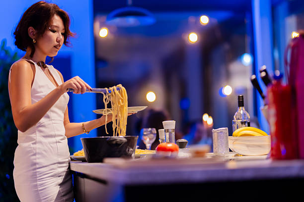 istock Woman in a stylish kitchen serving cooked pasta under creative ambient lighting 2214145750