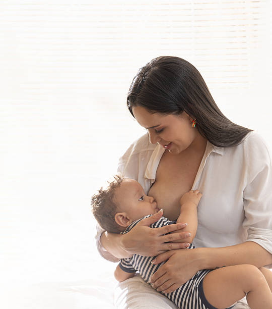 a young mother breastfeeding her baby in a softly lit home setting