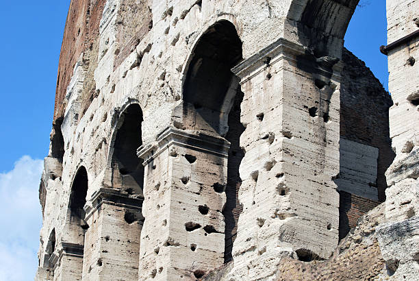 A close-up view of the Colosseum’s travertine arches and columns, marked with holes left by iron clamps removed during the Middle Ages. The texture highlights the passage of time and human interference with ancient architecture.