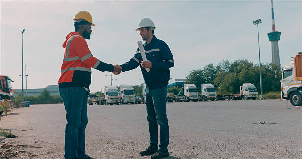 istock A professional male manager shaking hands and greeting with a hard hat, checking inventory and orders, shipping goods by air, sea, and domestic transportation to customers via app, an employee working in a distribution center in the logistics business.  a 2214155309