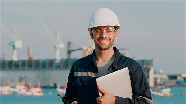 istock Portrait maintenance engineer smiling, handhold a computer notebook after a meeting to plan to repair or rebuild a large bulk ship damaged at a Commercial Shipyard. 2214155386